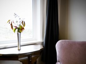 vase of flowers next to window and pink chair