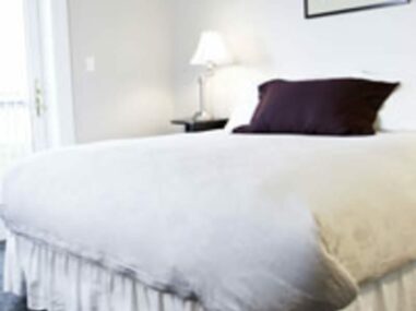 bed with white bedspread and brown pillow