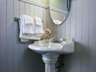 white pedestal sink with white towels and mirror