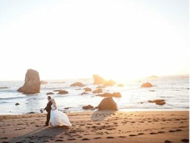 bride and groom walking along sandy beach