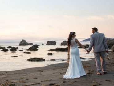 bride and groom walking on beach looking at each other